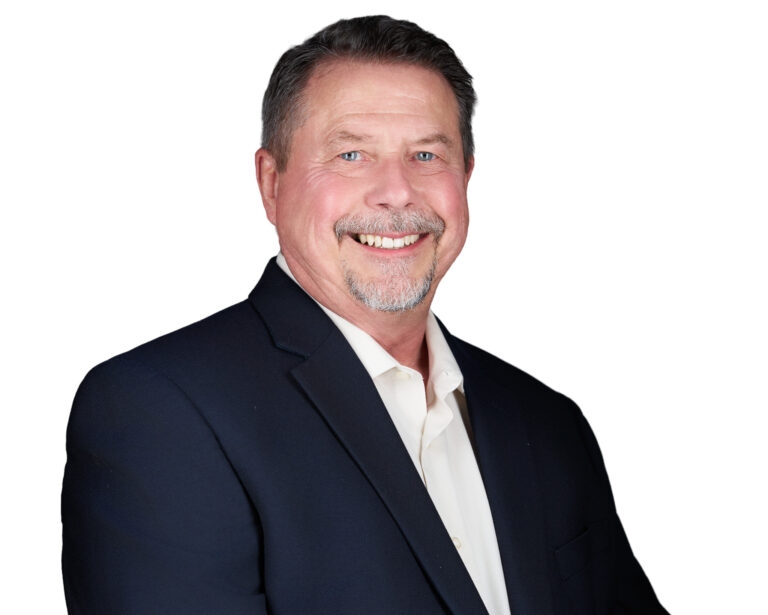 Professional headshot of a smiling man with graying hair and beard wearing a navy blazer against a white background