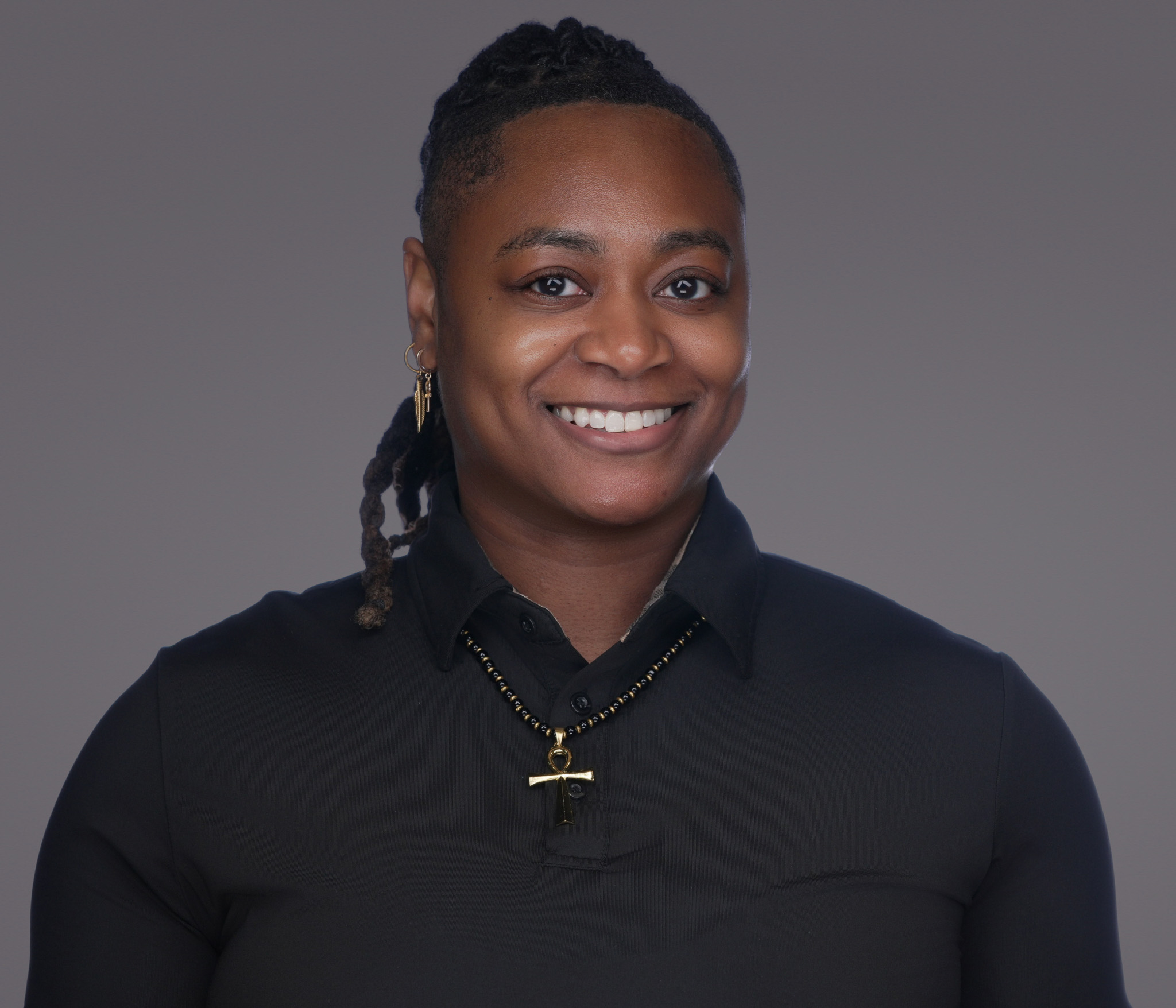 Woman with hair pulled back in a black top, studio headshot against a dark gray backdrop