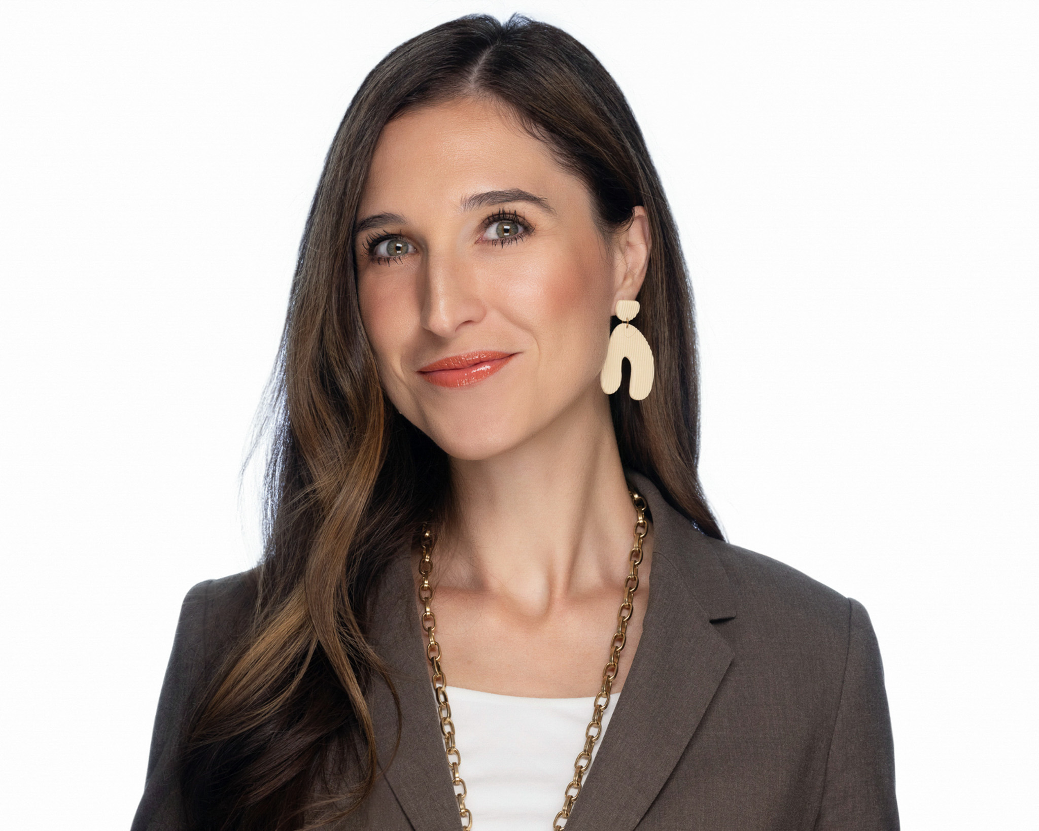 Woman with long brown hair in a dark top, studio headshot against a dark gray backdrop
