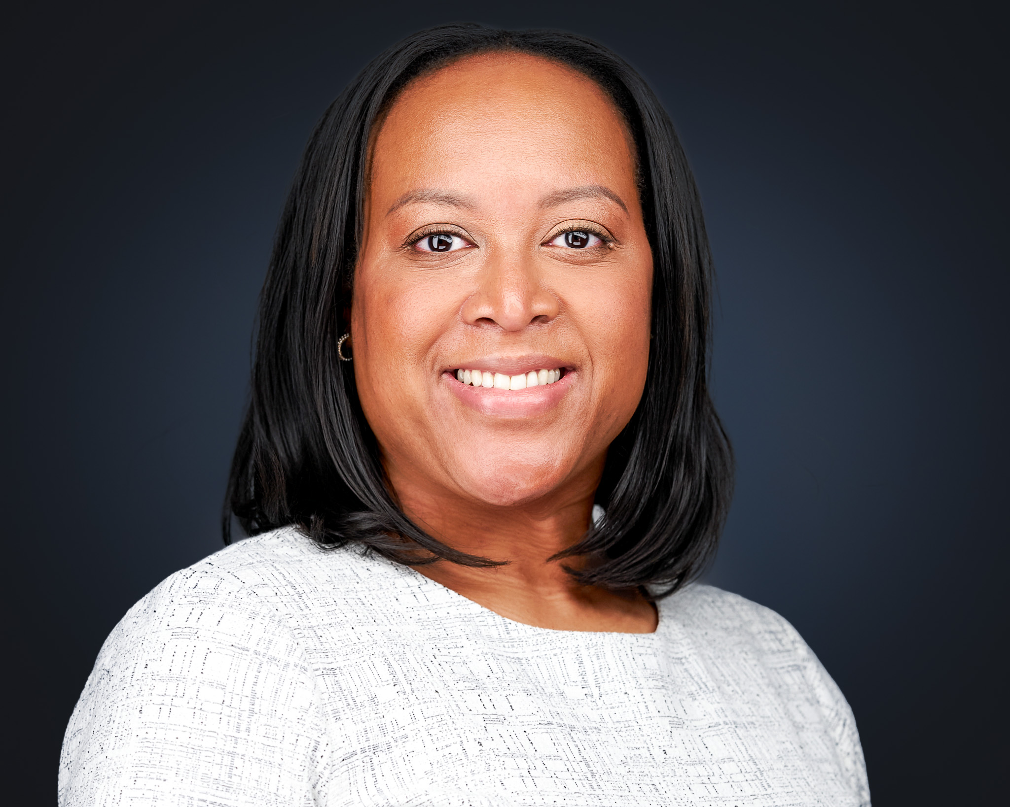 Smiling woman in a white sweater, studio headshot against a dark gray backdrop