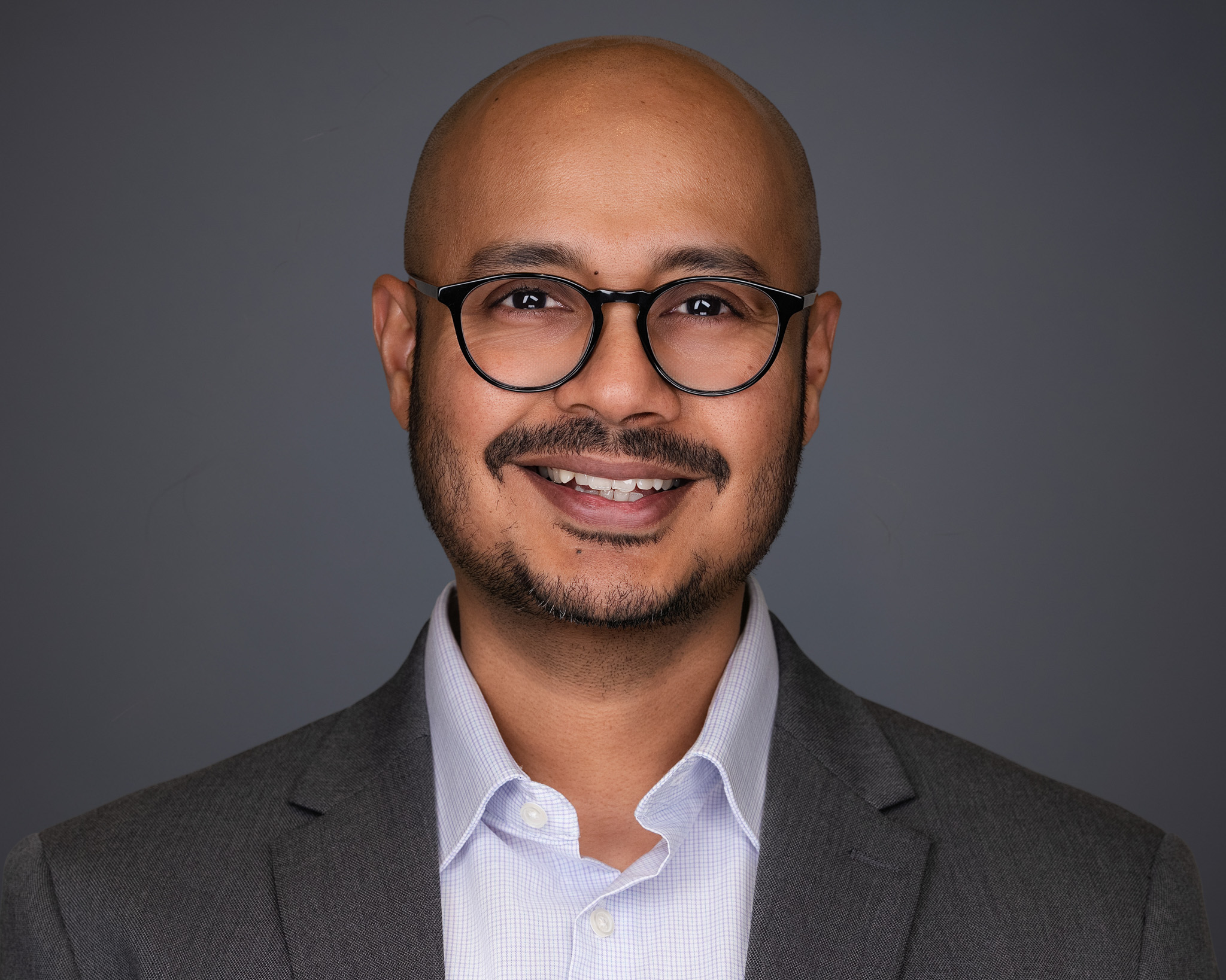 Executive portrait with an approachable expression against a studio backdrop