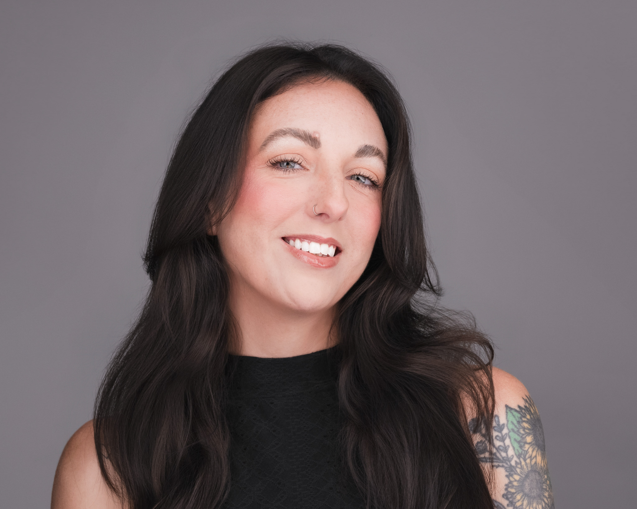 Smiling woman with long dark hair in a black top, studio headshot